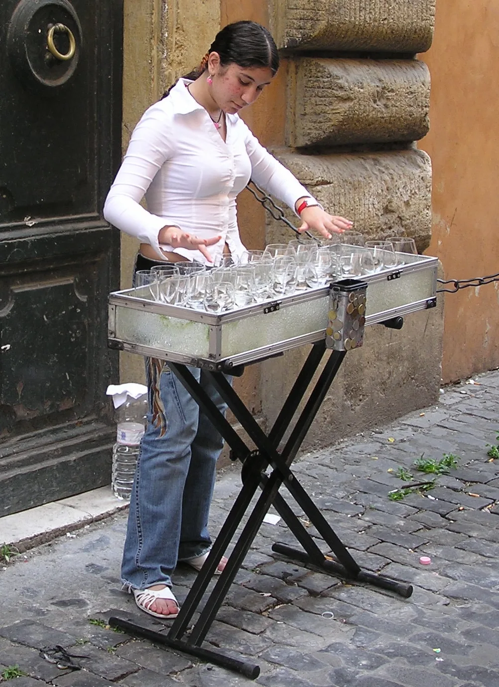 A glass harp, an ancestor of the glass armonica, being played in Rome. The rims of wine glasses filled with water are ru