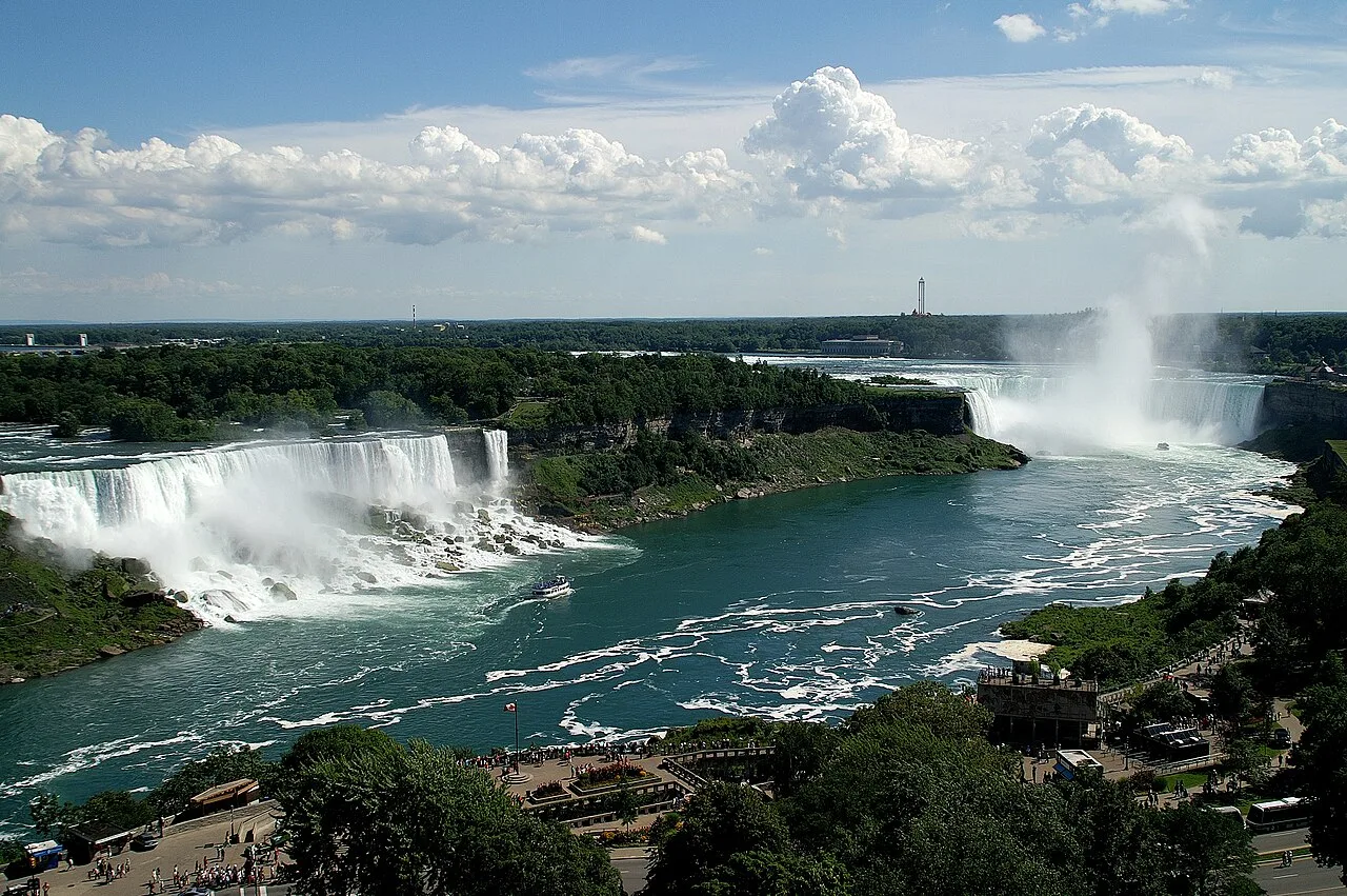 High view of Niagara Falls as viewed from the Canadian side of the river. The image includes American Falls, Bridal Veil Falls, and Horseshoe Falls